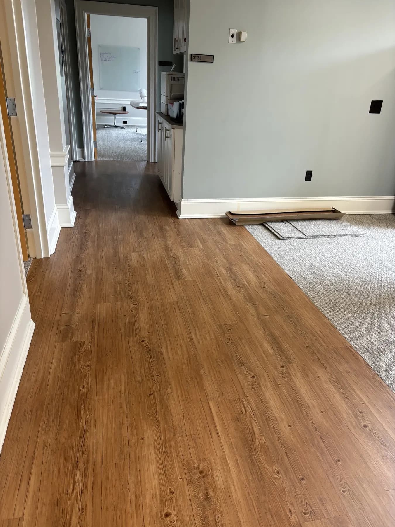 Finished warm wood-look vinyl plank running down the office suite hallway