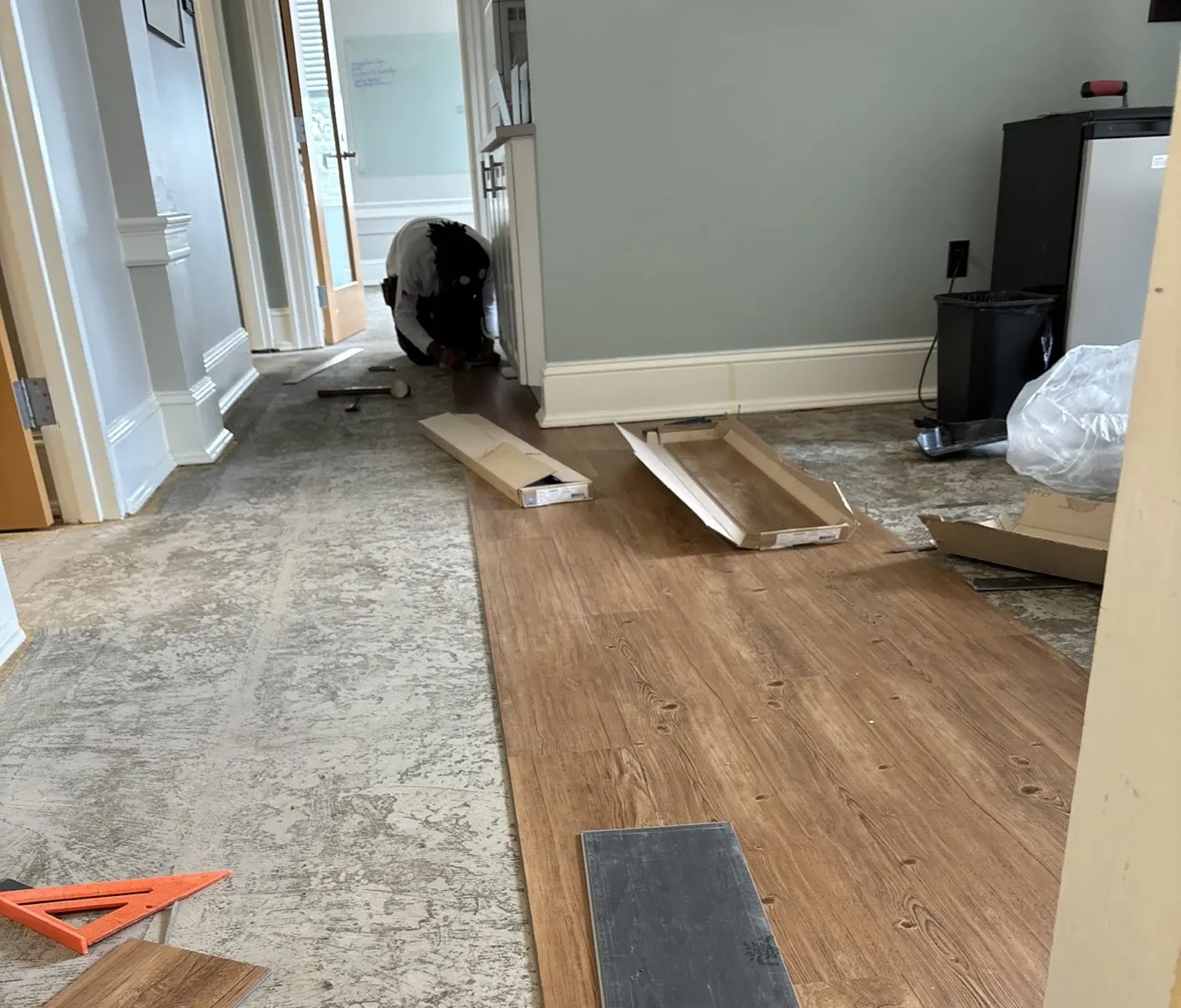 In progress: wood-look vinyl plank being laid over the prepped subfloor in an office hallway