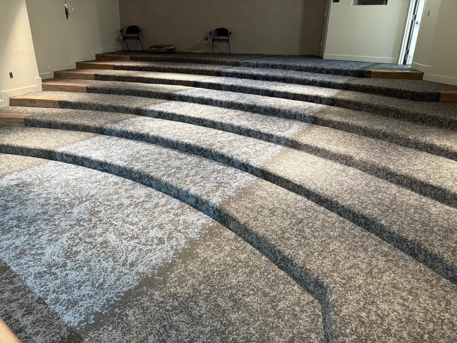 Patterned carpet tile across the curved, tiered seating rows of the auditorium