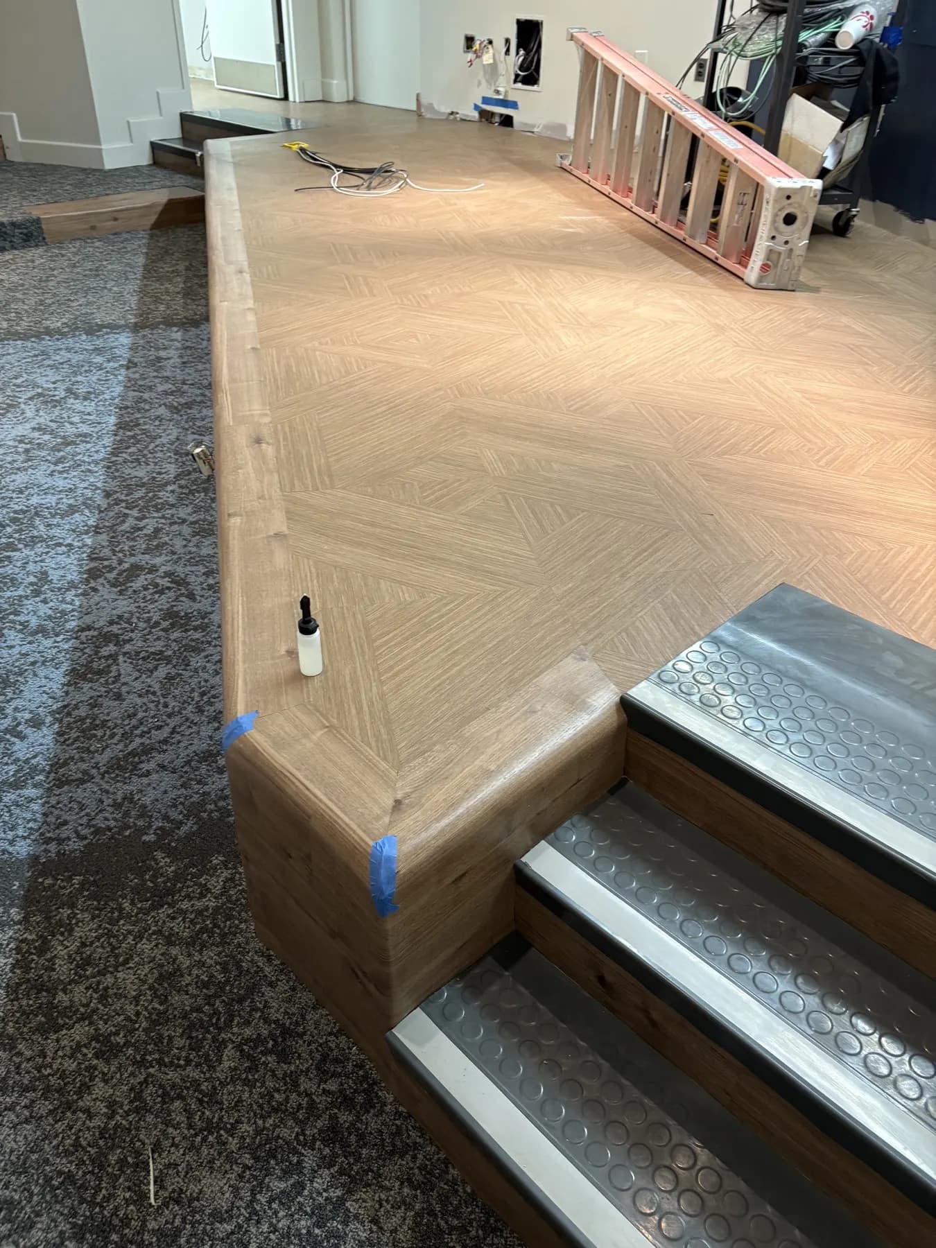 In progress: the auditorium stage platform being finished, with carpet tile going in around it
