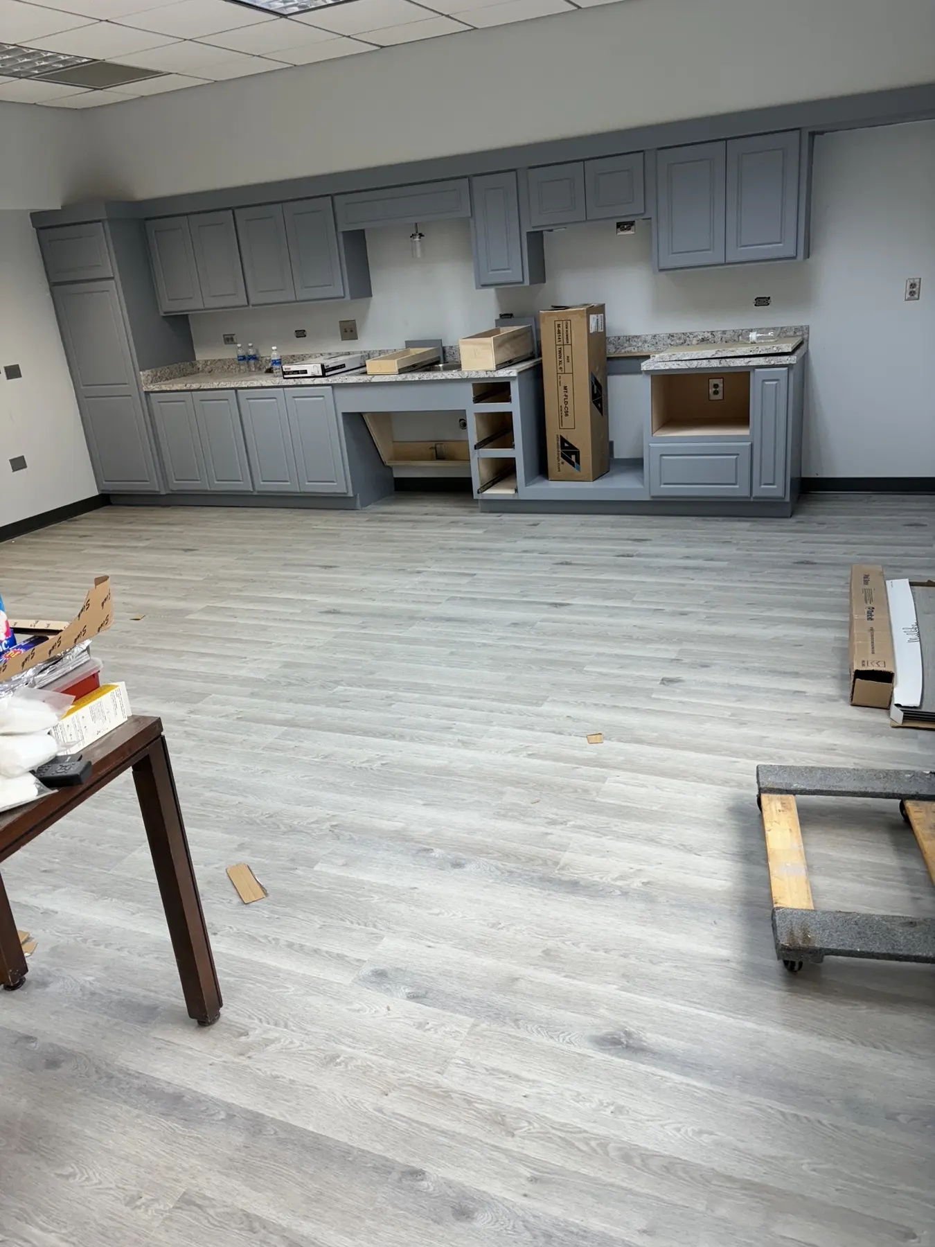 The same break room finished in gray wood-look luxury vinyl plank up to the cabinets